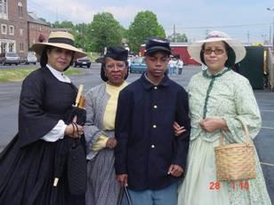 Four persons in Civil War era clothing and uniforms pose for the camera.