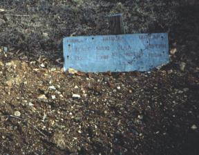 Grave marked with a stenciled sheet metal plaque